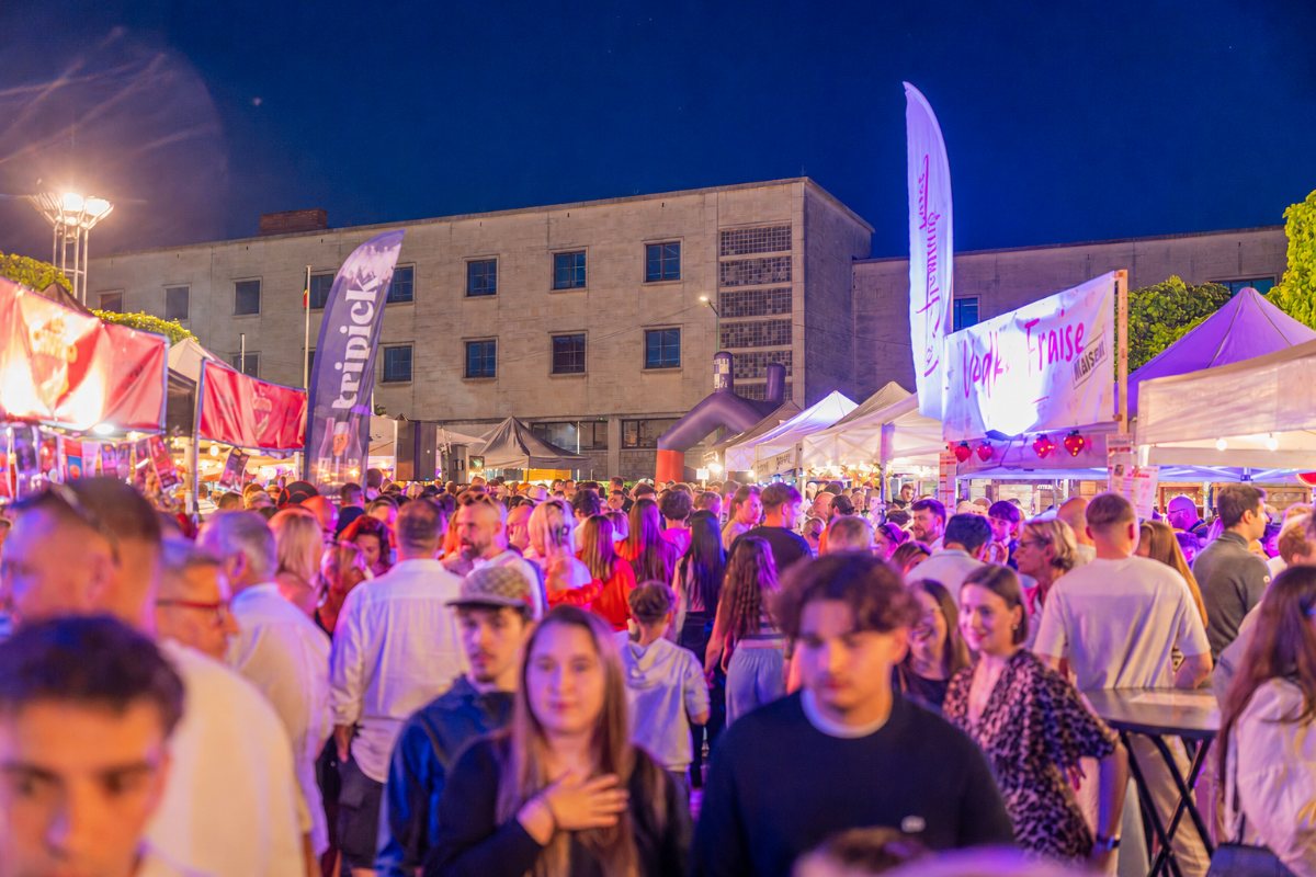 Ambiance d'un soir d'apéro au village, place pleine de monde et de chalets éclairés